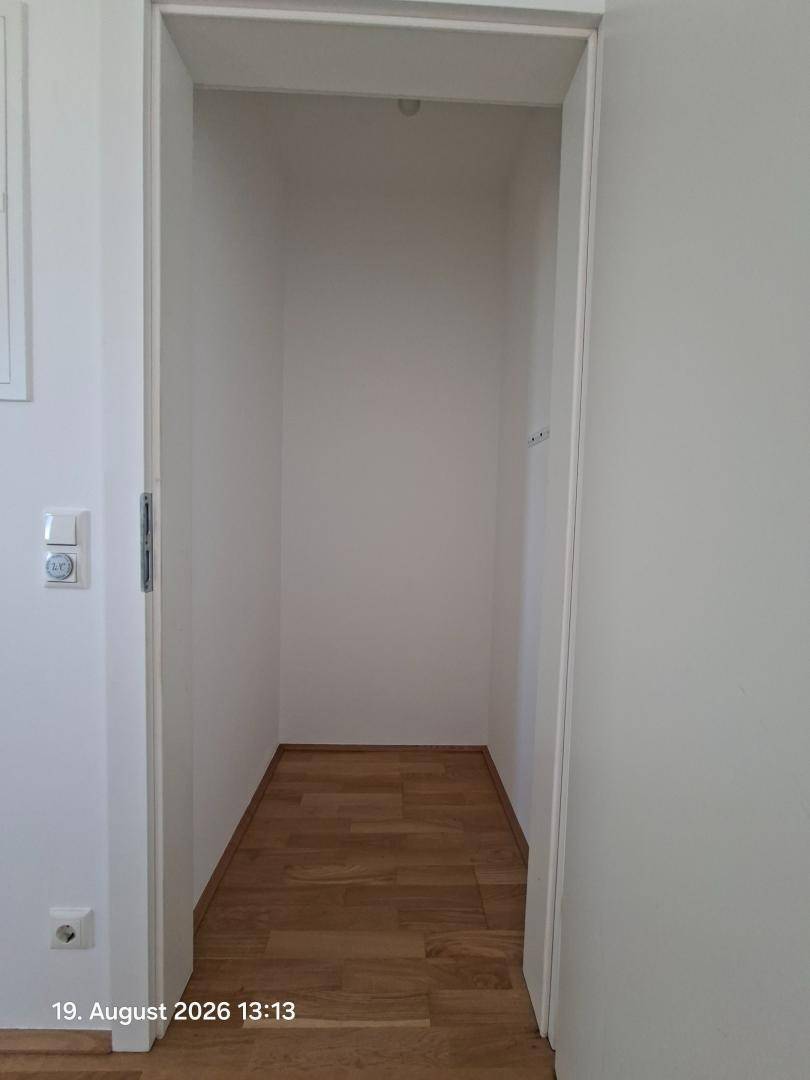 Kleiner Abstellraum mit Holzparkettboden und weißen Wänden, ideal für zusätzlichen Stauraum.