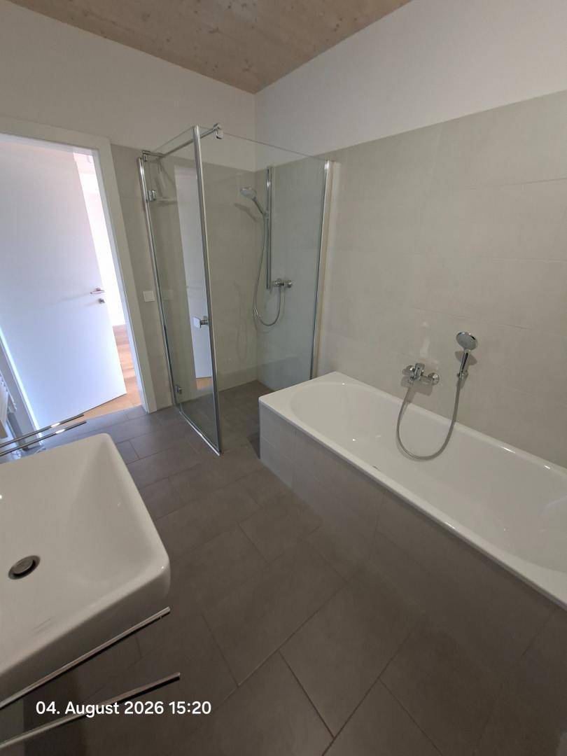 Modernes Badezimmer mit Badewanne, Duschkabine und großformatigen Fliesen.