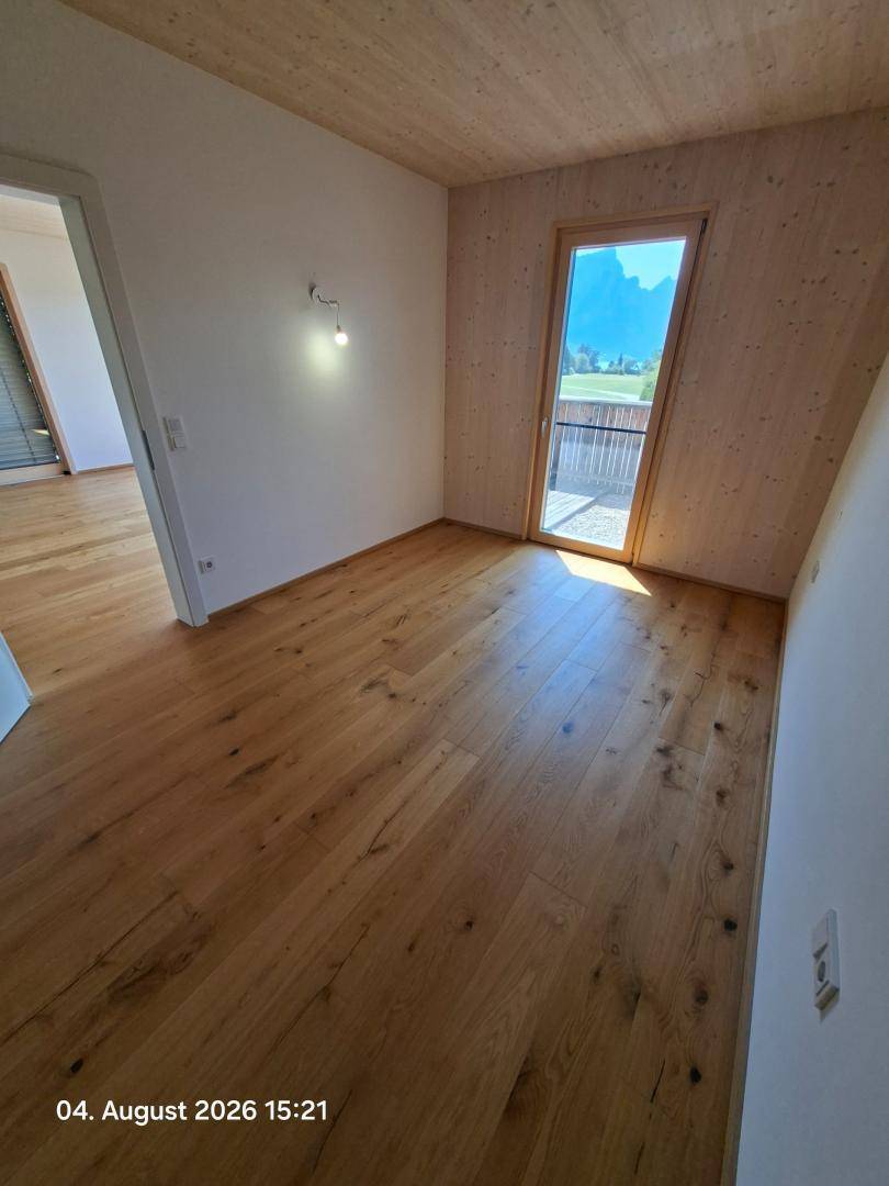 Geräumiges Schlafzimmer mit Holzboden und Zugang zu einem Balkon mit Bergblick.