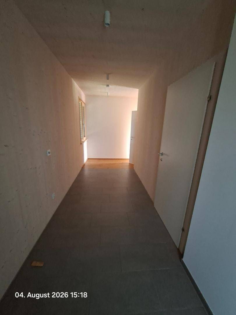 Langer Flur mit Fliesenboden und Holzwänden, der zu weiteren Räumen führt.