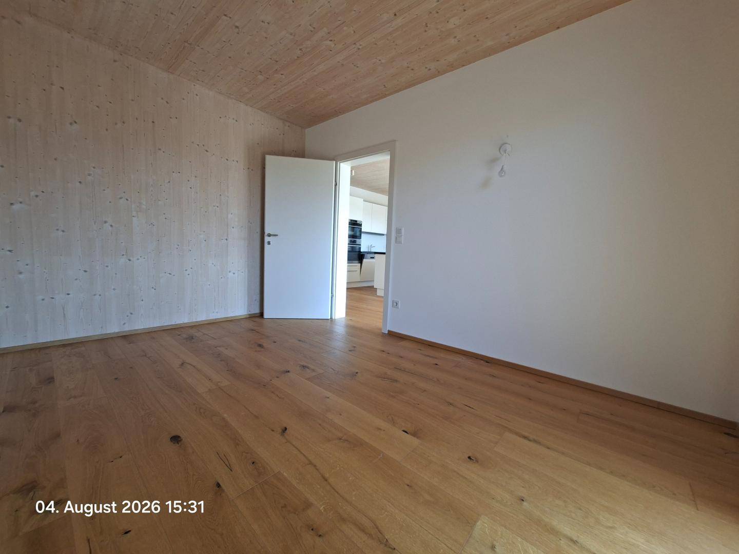 Geräumiges Zimmer mit Holzboden und Holzwänden, bereit für individuelle Gestaltung.