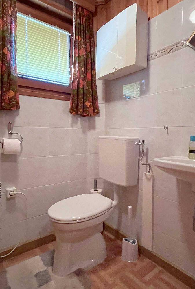 Separates WC mit Fenster, Toilette und kleinem Waschbecken.