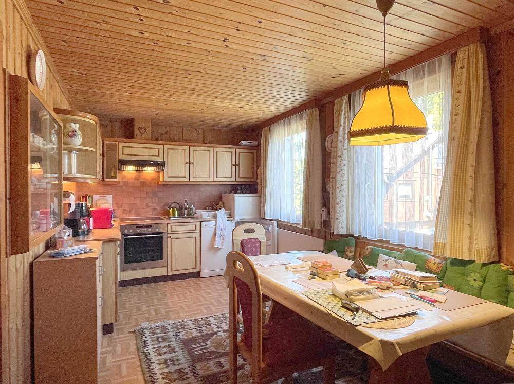 Traditionelle Küche mit Holzvertäfelung, Essbereich und Blick ins Grüne.
