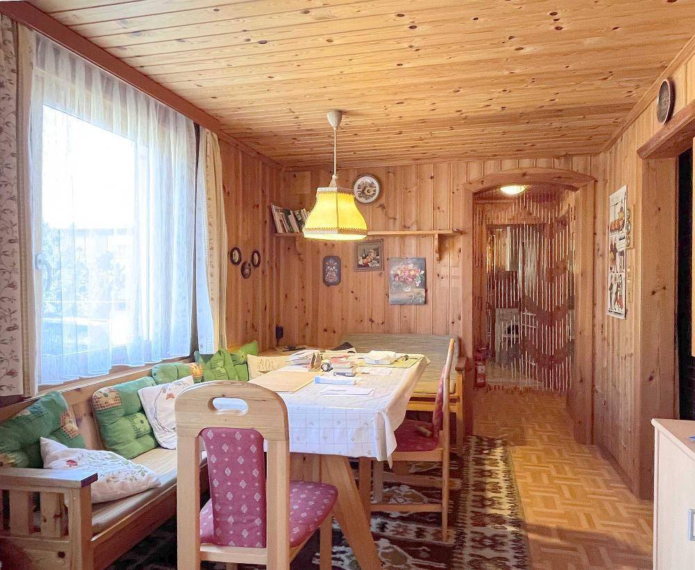 Gemütlicher Wohn- und Essbereich mit Holzvertäfelung und Zugang zum Flur.