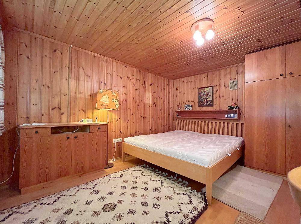 Schlafzimmer im Landhausstil mit Holzvertäfelung, Doppelbett und Kleiderschrank.