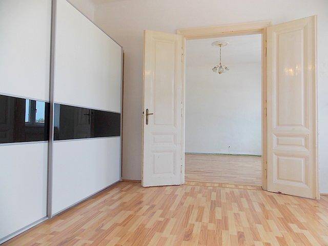 Schlafzimmer mit modernem Schiebetürenschrank und hellem Laminatboden, bereit zur Einrichtung.