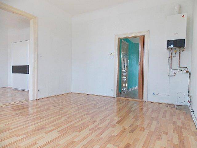 Heller Raum mit Laminatboden und sichtbarem Warmwasserbereiter an der Wand.