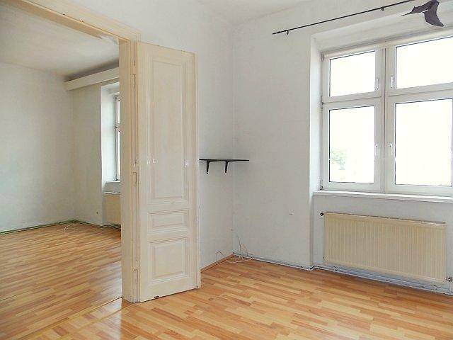Geräumiges Zimmer mit Laminatboden und Zugang zu einem weiteren hellen Raum.