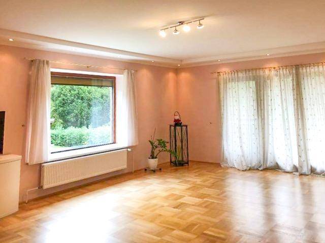 Helles Wohnzimmer mit Parkettboden, großen Fenstern und rosafarbenen Wänden.