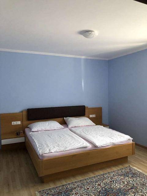 Schlafzimmer mit blauen Wänden, Doppelbett und Holzboden, ausgestattet mit einem Teppich.