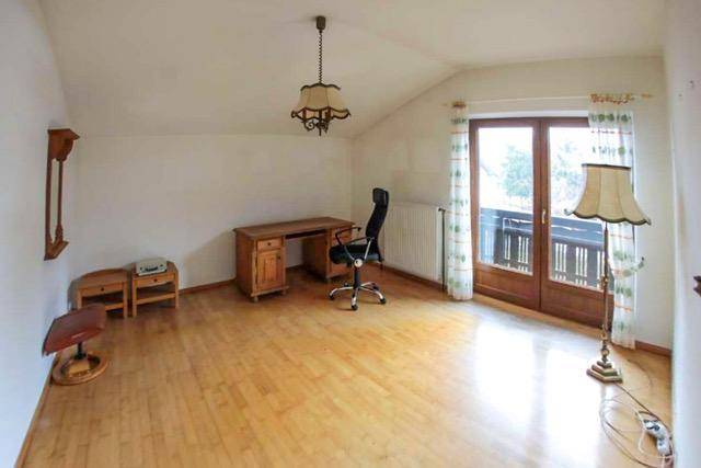 Helles Arbeitszimmer mit Holzboden, Schreibtisch und Zugang zu einem kleinen Balkon.