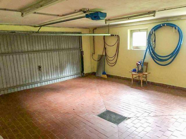 Geräumige Garage mit Rolltor, gefliestem Boden und einem Fenster.