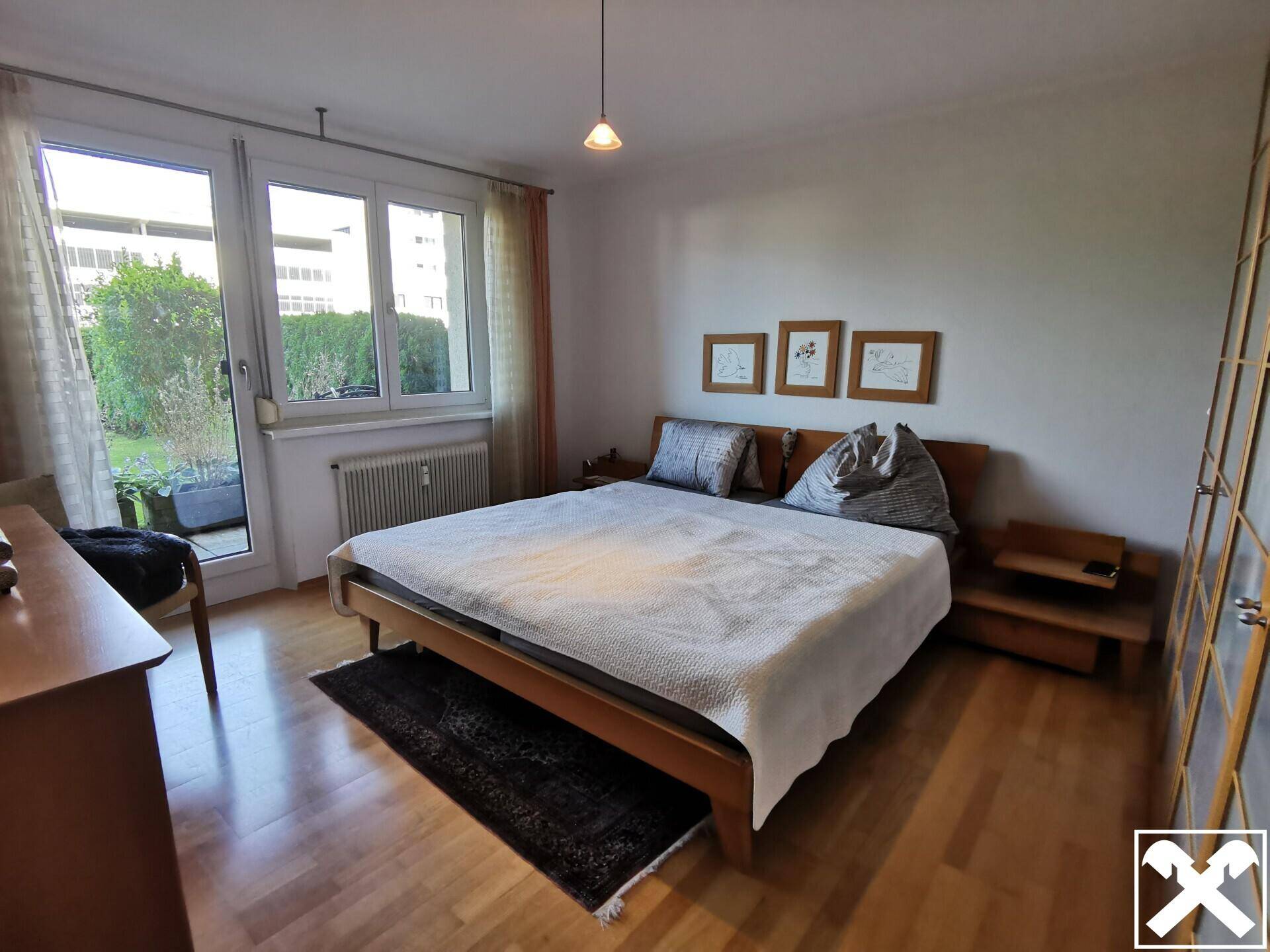 Helles Schlafzimmer mit Doppelbett, Holzboden und direktem Zugang zu einem kleinen Außenbereich.