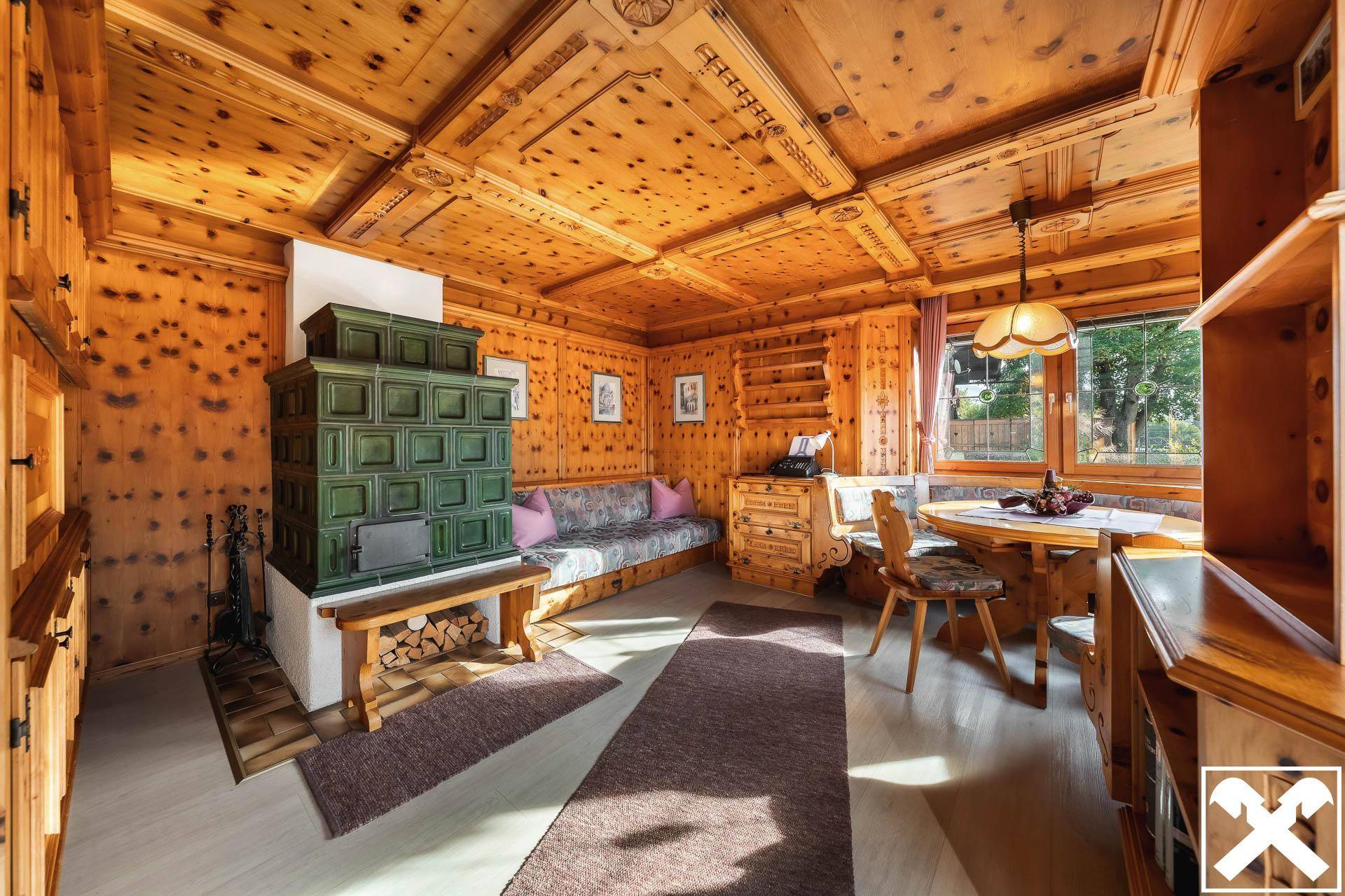 Gemütlicher Wohn-Essbereich im alpinen Stil mit Kachelofen und Holztäfelung.