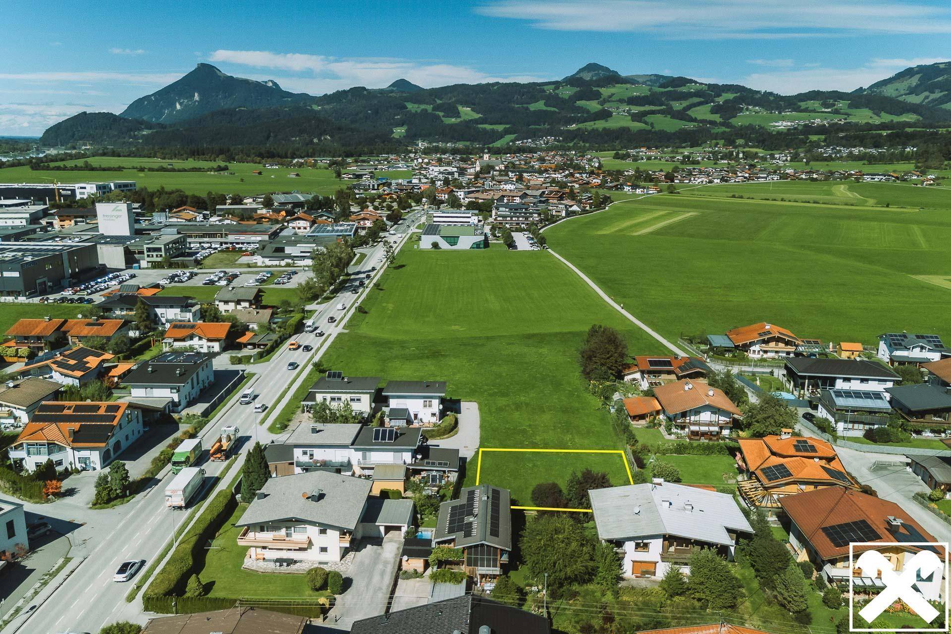 Weitläufige Luftaufnahme des Baugrundstücks in einer Siedlung mit guter Verkehrsanbindung und Bergblick.