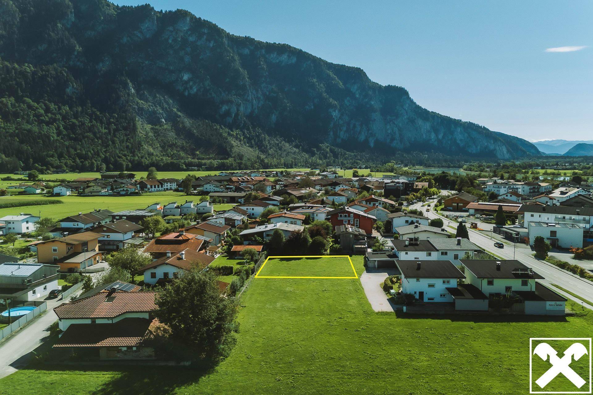 Übersicht des Baugrundstücks in ländlicher Umgebung, umgeben von Wohnhäusern und Bergen.