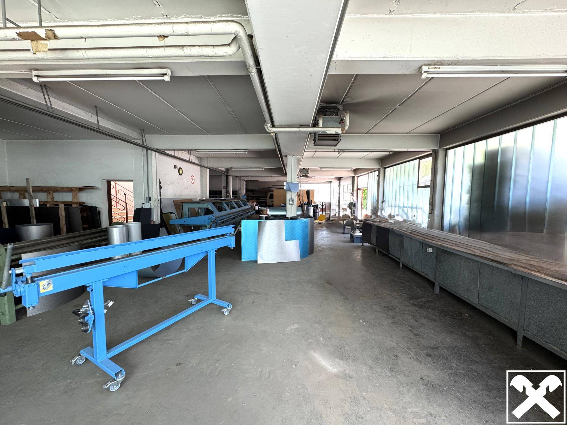 Industrielle Werkstatt mit Maschinen, sichtbaren Rohren und großen Fenstern, die viel Licht spenden.