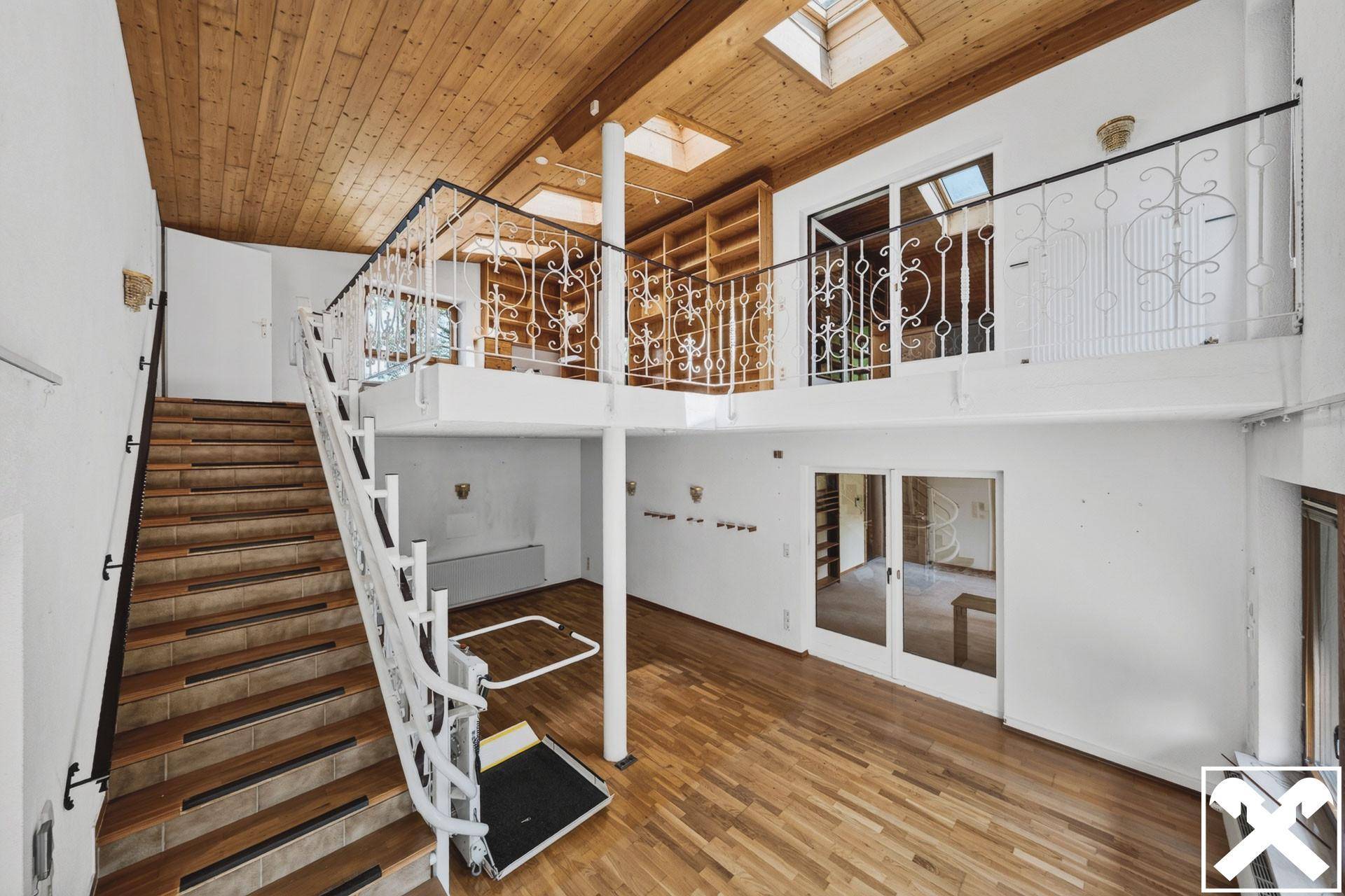 Geräumiger Flur mit Holztreppe, Galerie und einem Treppenlift für Barrierefreiheit.