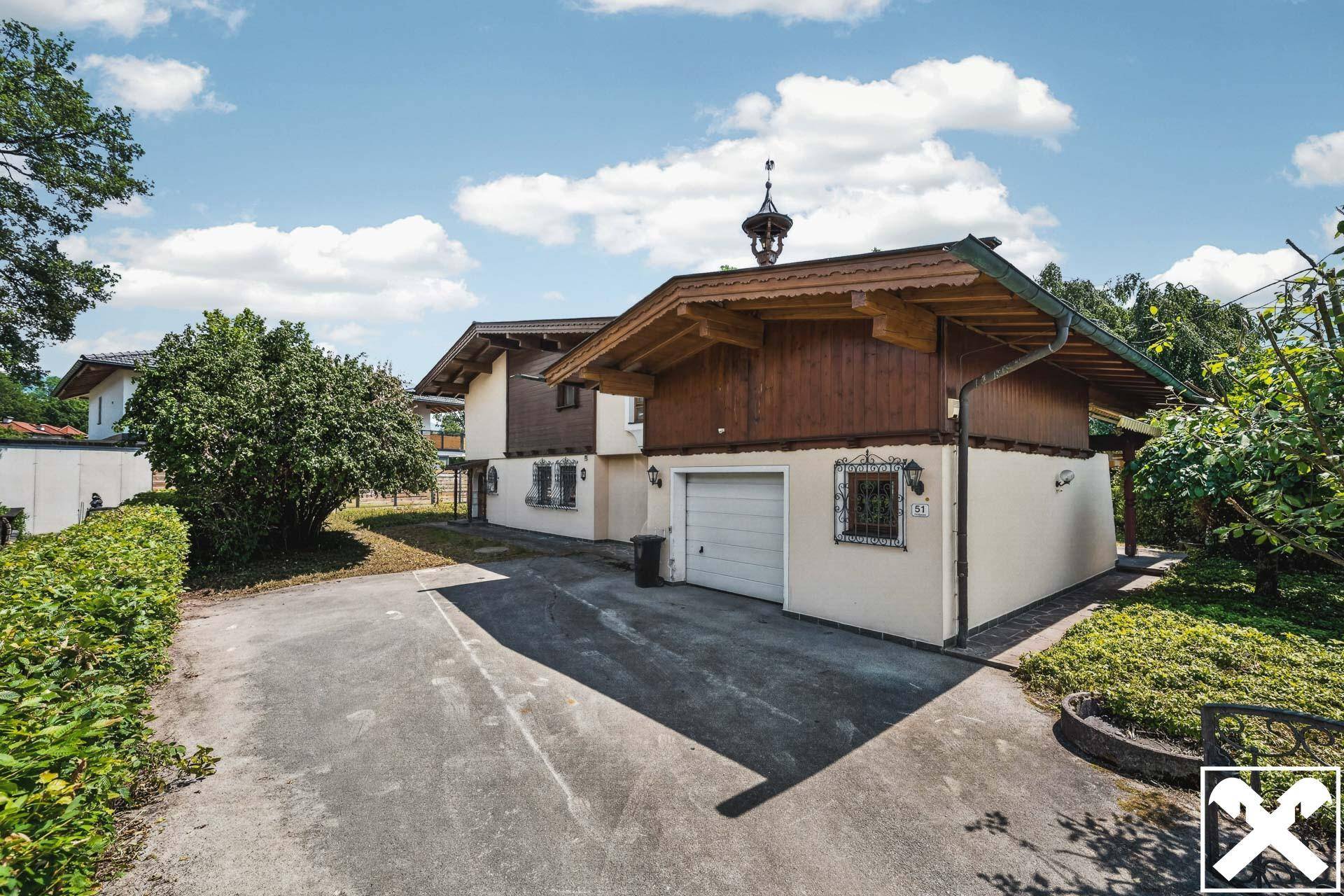 Rückansicht des Hauses mit Garage, Zufahrt und traditioneller Holzverkleidung.