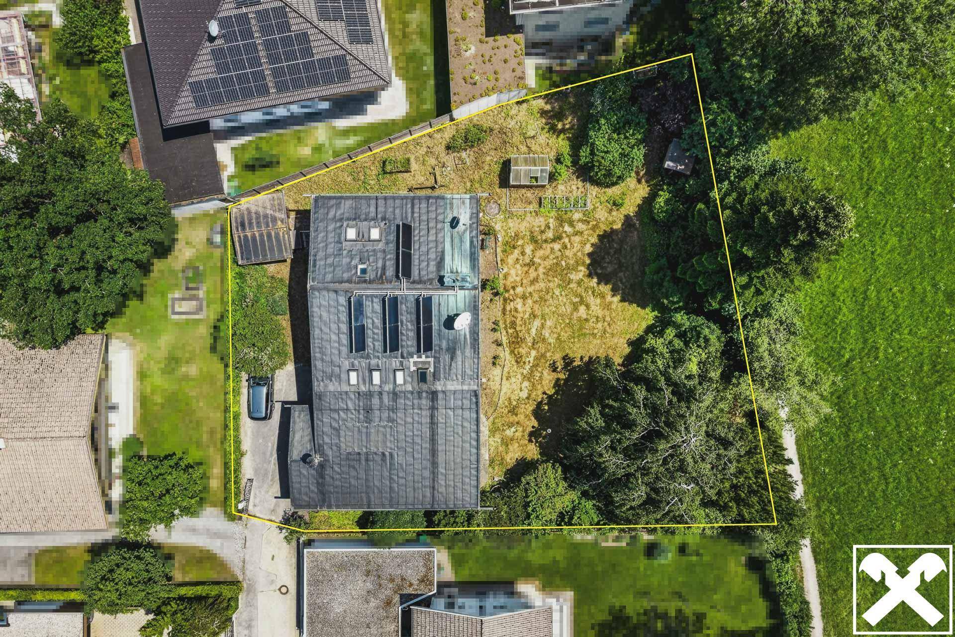 Luftaufnahme eines Wohnhauses mit großem Grundstück, Garten und angrenzenden Grünflächen, die Grundstücksgrenzen sind markiert.