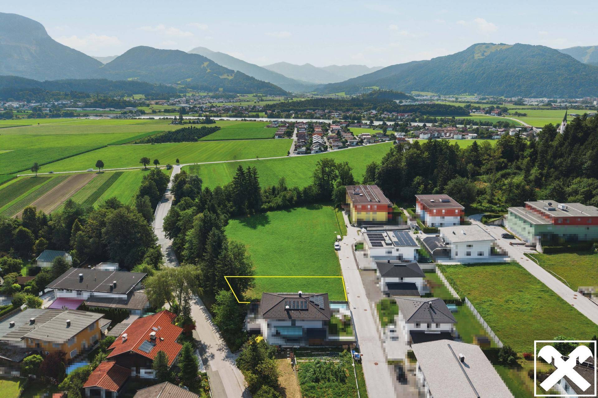 Weitläufige Luftaufnahme einer ländlichen Wohngegend mit markiertem Grundstück und Bergblick.