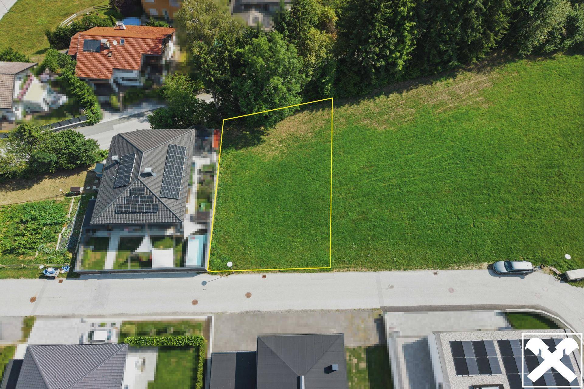 Nahaufnahme aus der Luft eines Baugrundstücks neben einem modernen Haus mit Solaranlage.