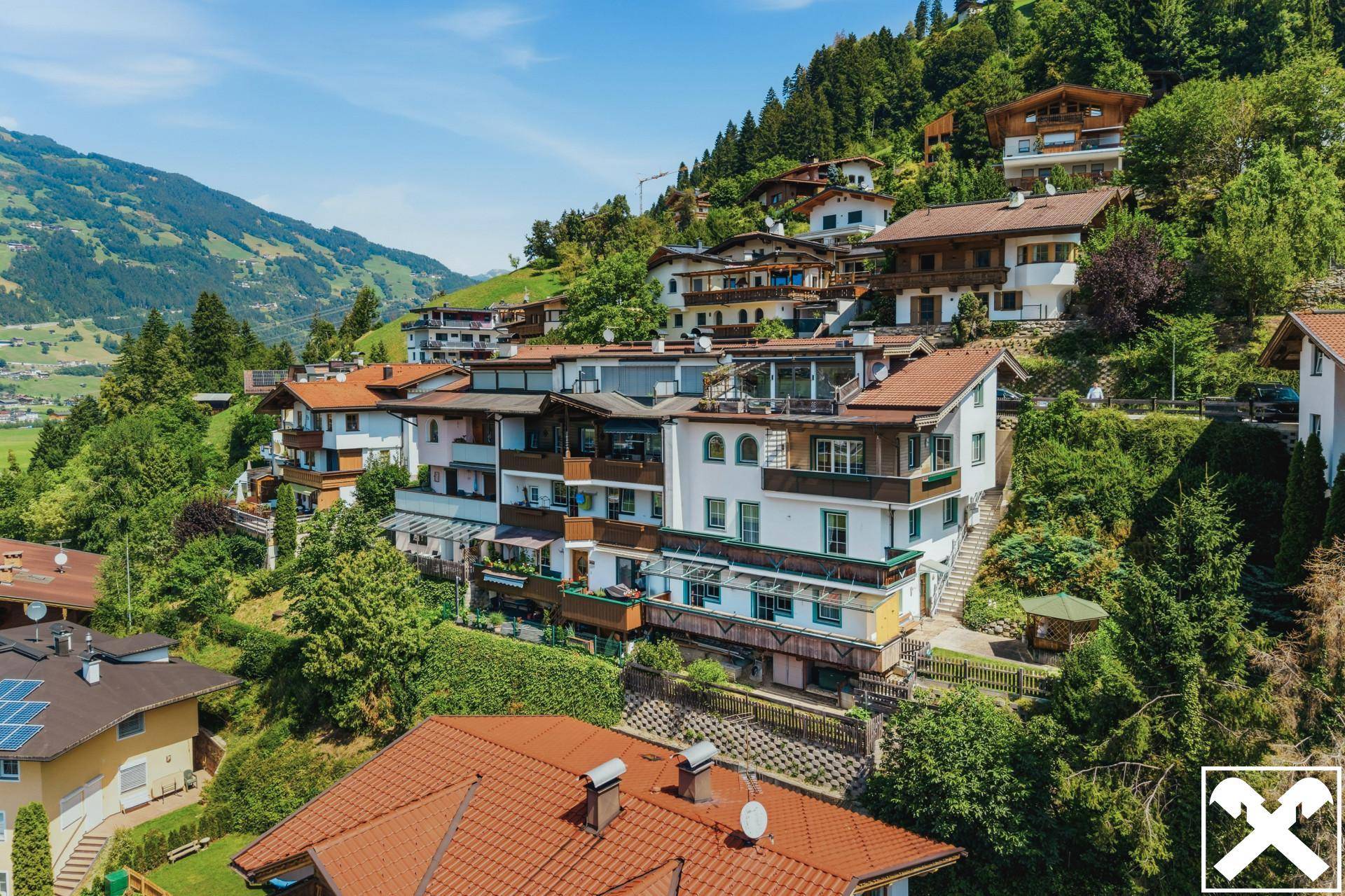 Übersicht der Immobilie in einer Wohnsiedlung am Hang mit Blick auf die umliegende Natur.
