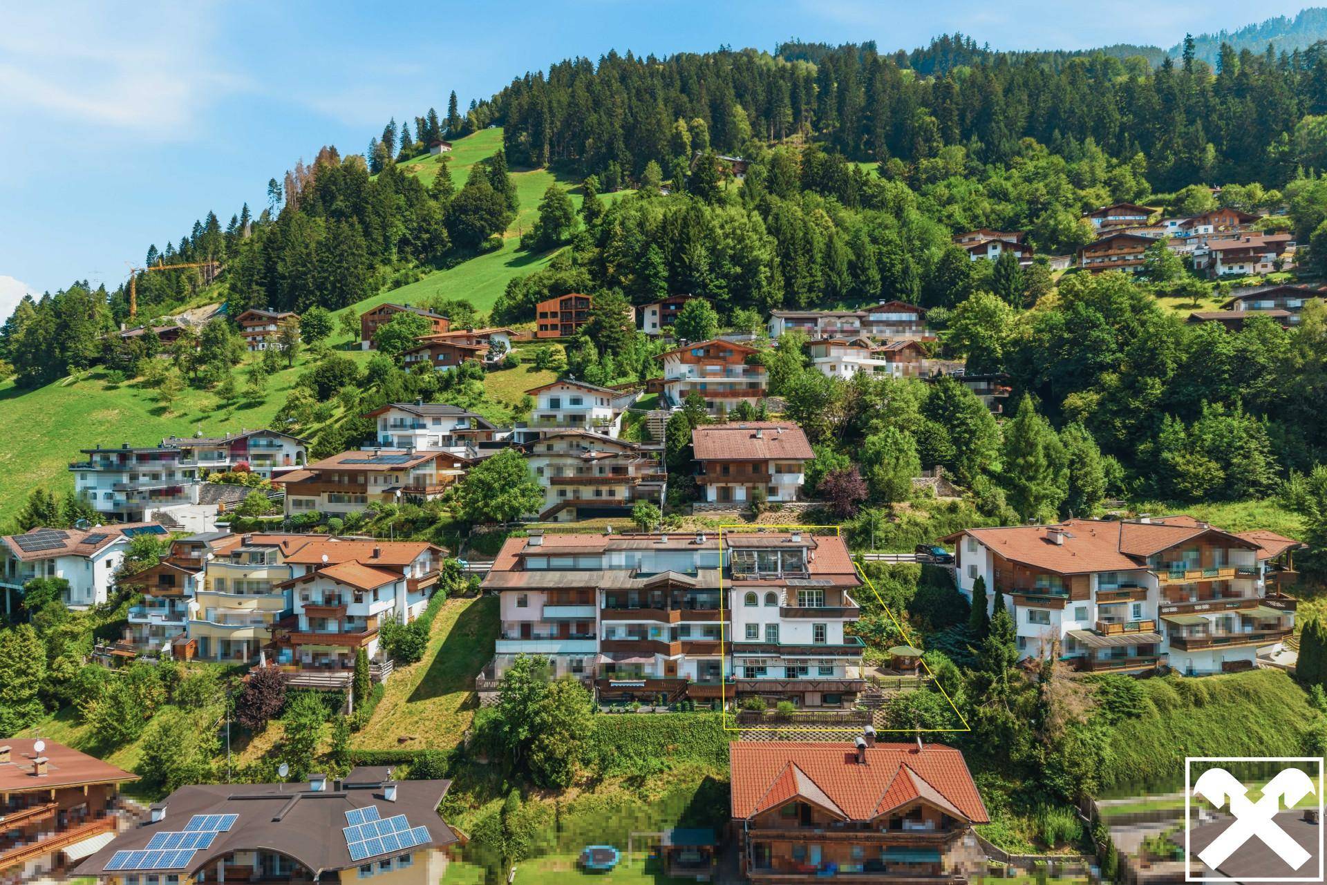 Luftaufnahme der Immobilie in Hanglage, umgeben von weiteren Wohnhäusern und grüner Natur.