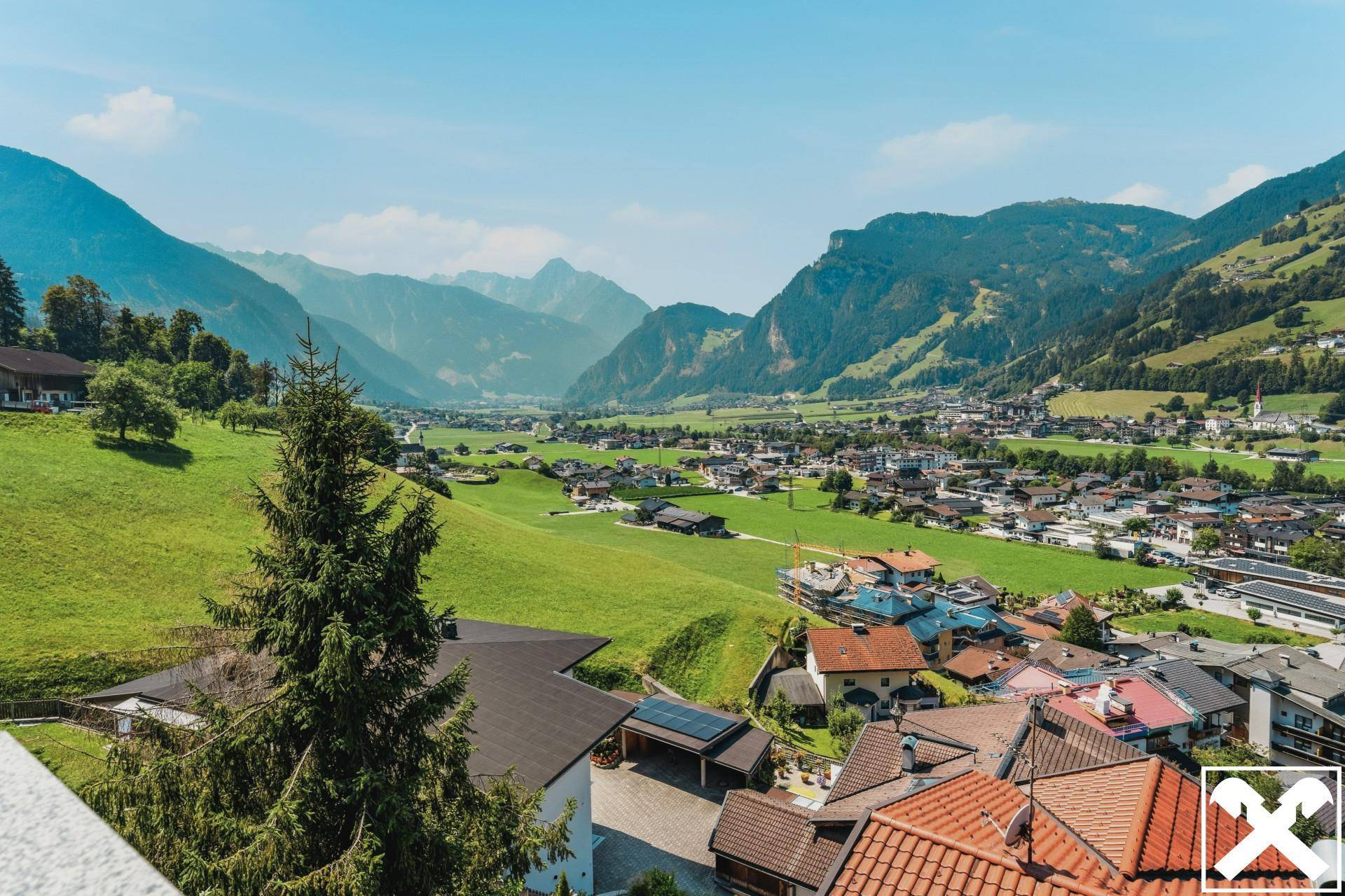 Panoramablick auf die umliegende Berglandschaft und das Tal mit Siedlung.