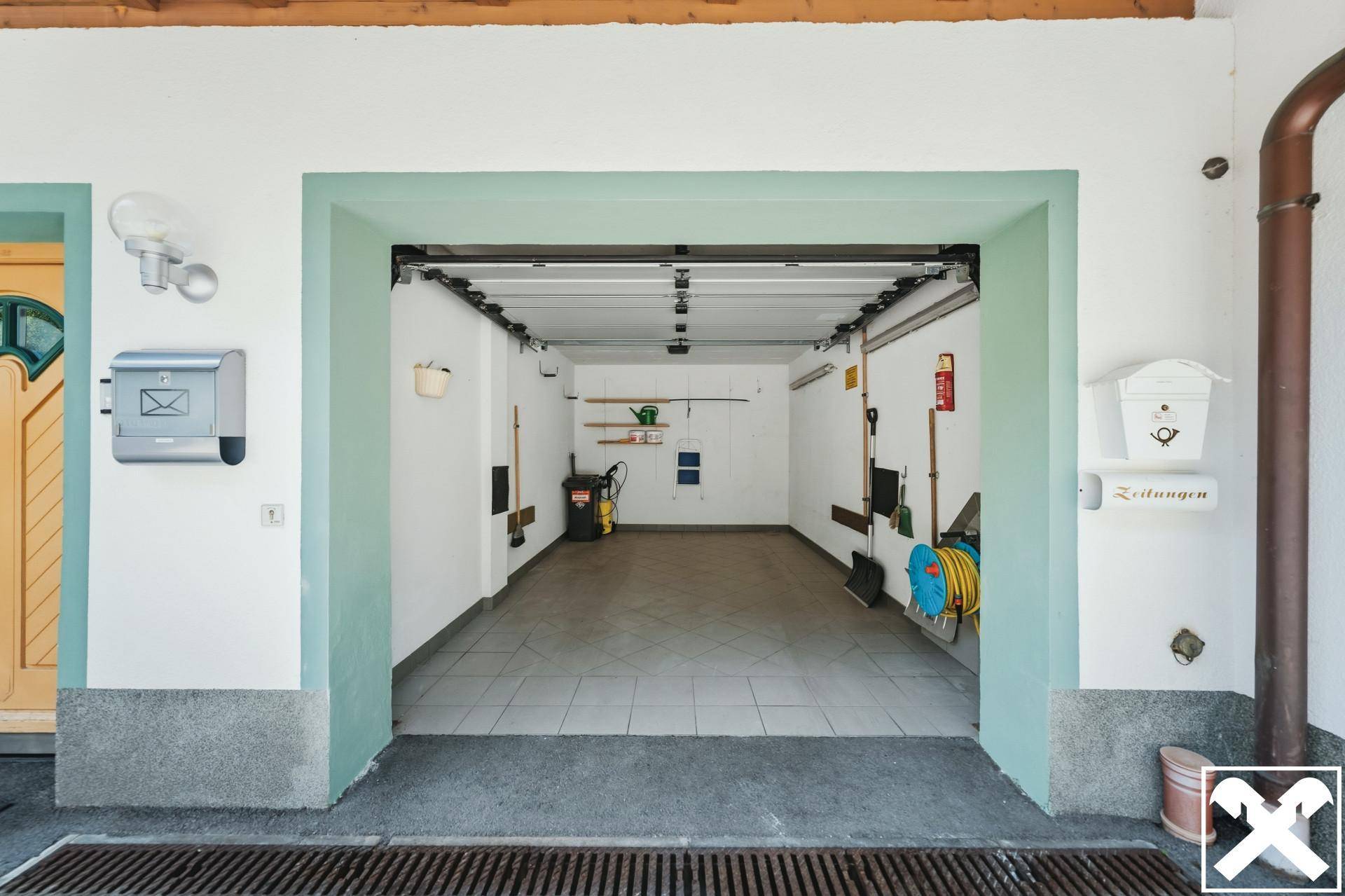 Geräumige Garage mit Fliesenboden, Stauraum und direktem Zugang zum Haus.