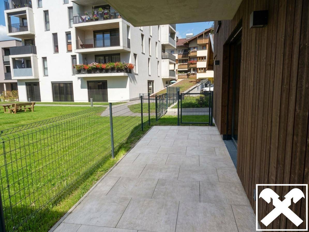 Gepflasterte Terrasse mit Blick auf die gemeinschaftliche Grünfläche und moderne Wohngebäude.