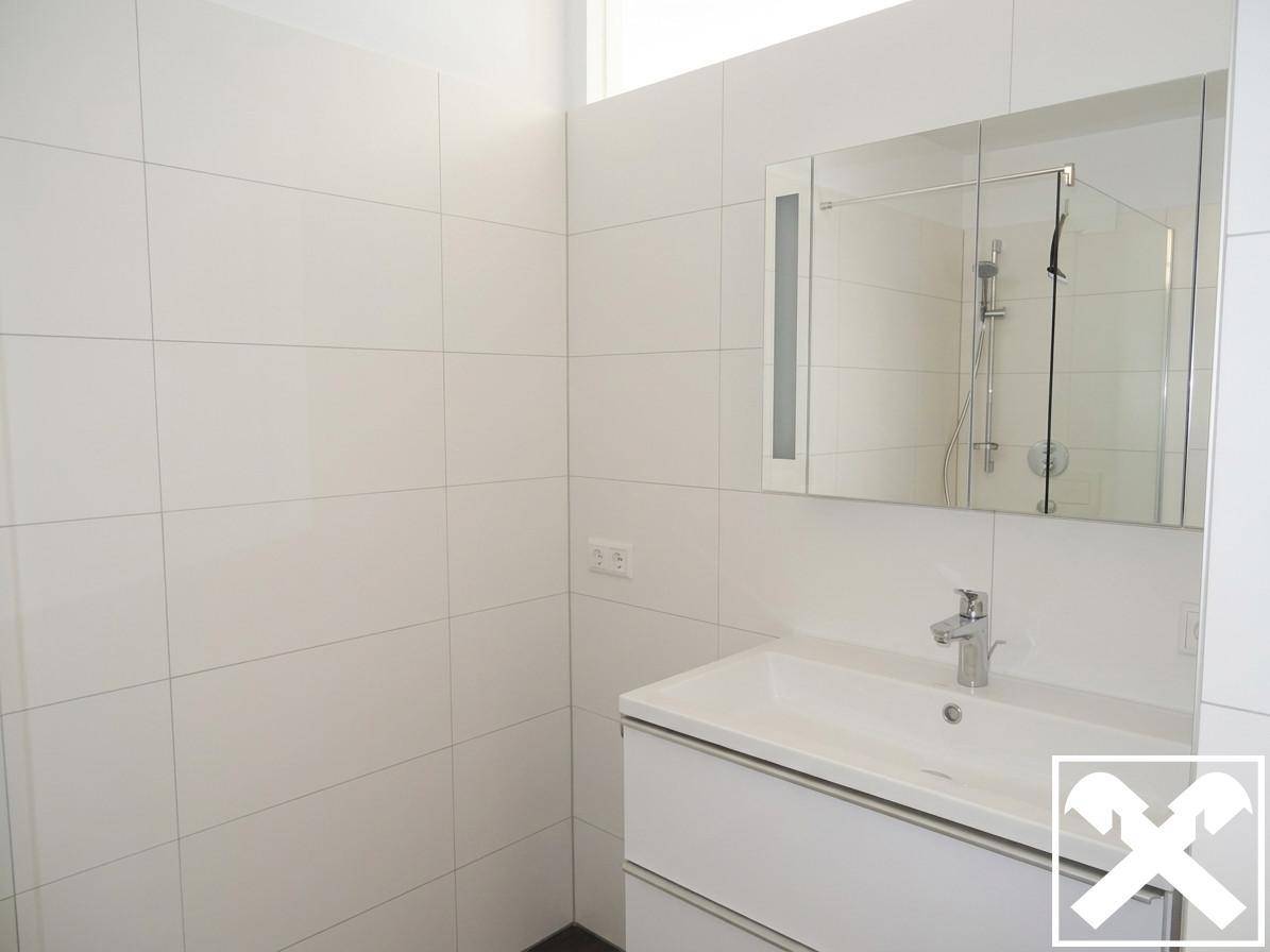 Modernes Badezimmer mit weißen Fliesen, Einzelwaschbecken und Spiegelschrank.