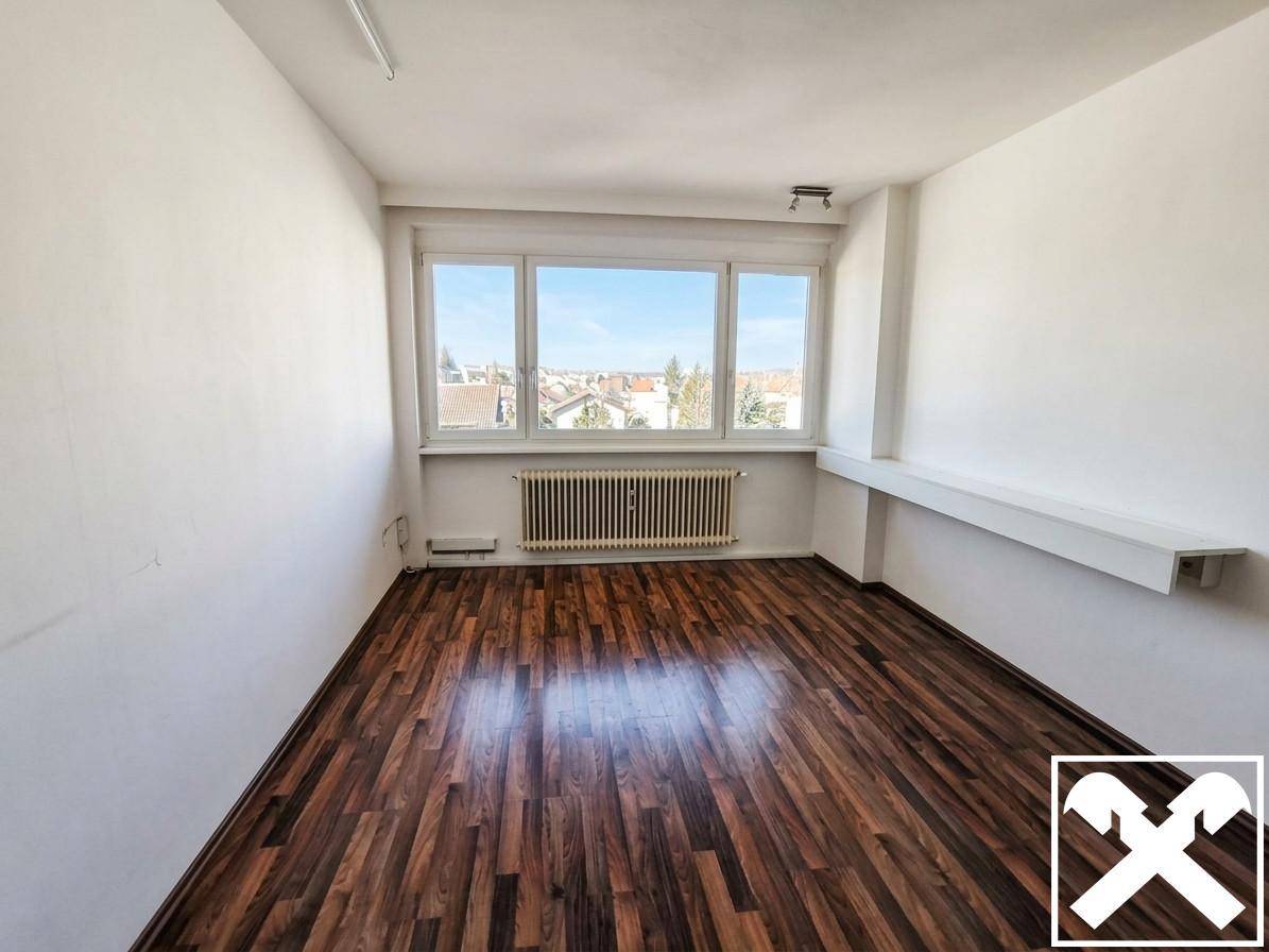 Heller Wohnraum mit Laminatboden, großen Fenstern und einem Heizkörper, ideal für individuelle Gestaltung.