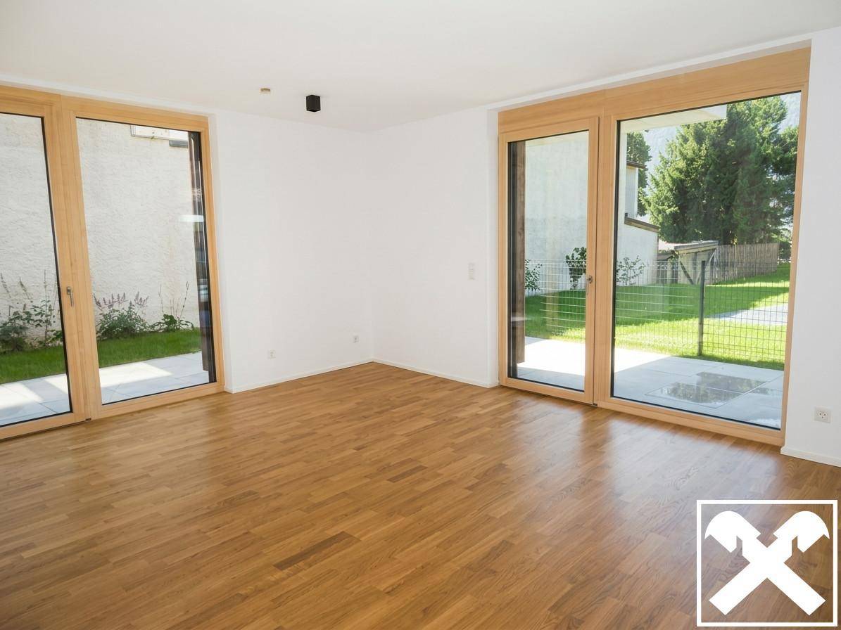 Heller Wohnraum mit Eichenparkettboden und großen Fenstern mit Zugang zum Garten.