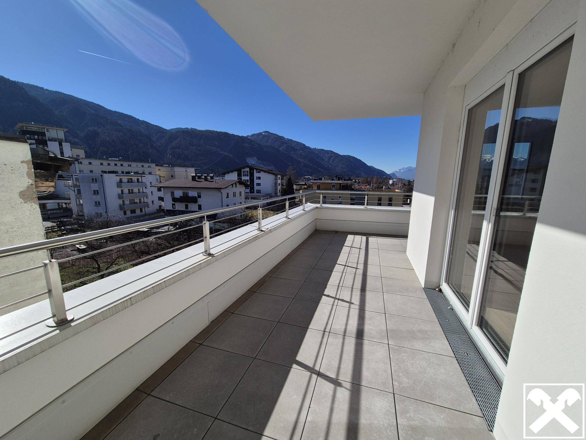 Heller Balkon mit Fliesenboden und Geländer, bietet einen schönen Blick auf die Berge.