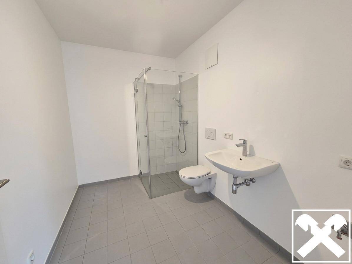 Modernes Badezimmer mit Duschkabine, Wand-WC und Waschbecken in minimalistischem Design.