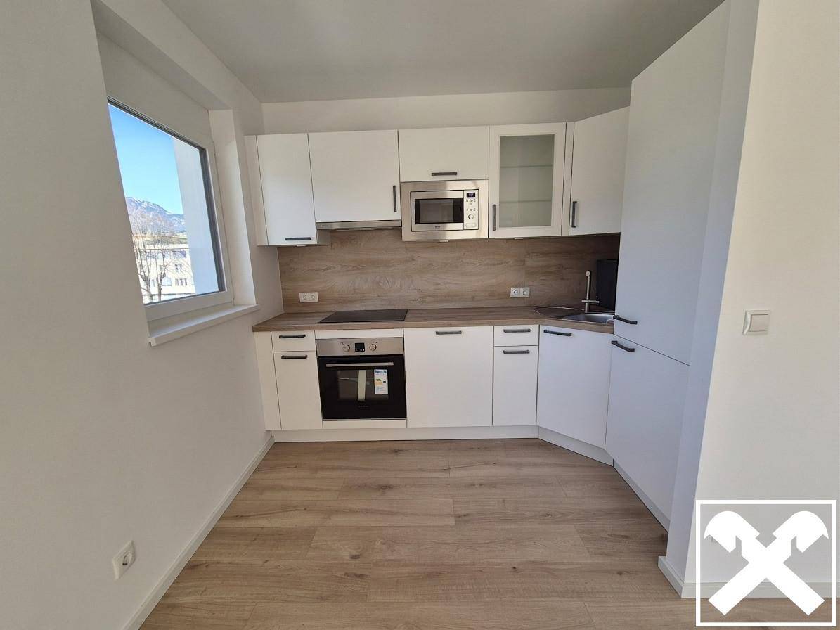 Moderne Einbauküche in Weiß mit Holzoptik-Arbeitsplatte und Fenster mit Bergblick.
