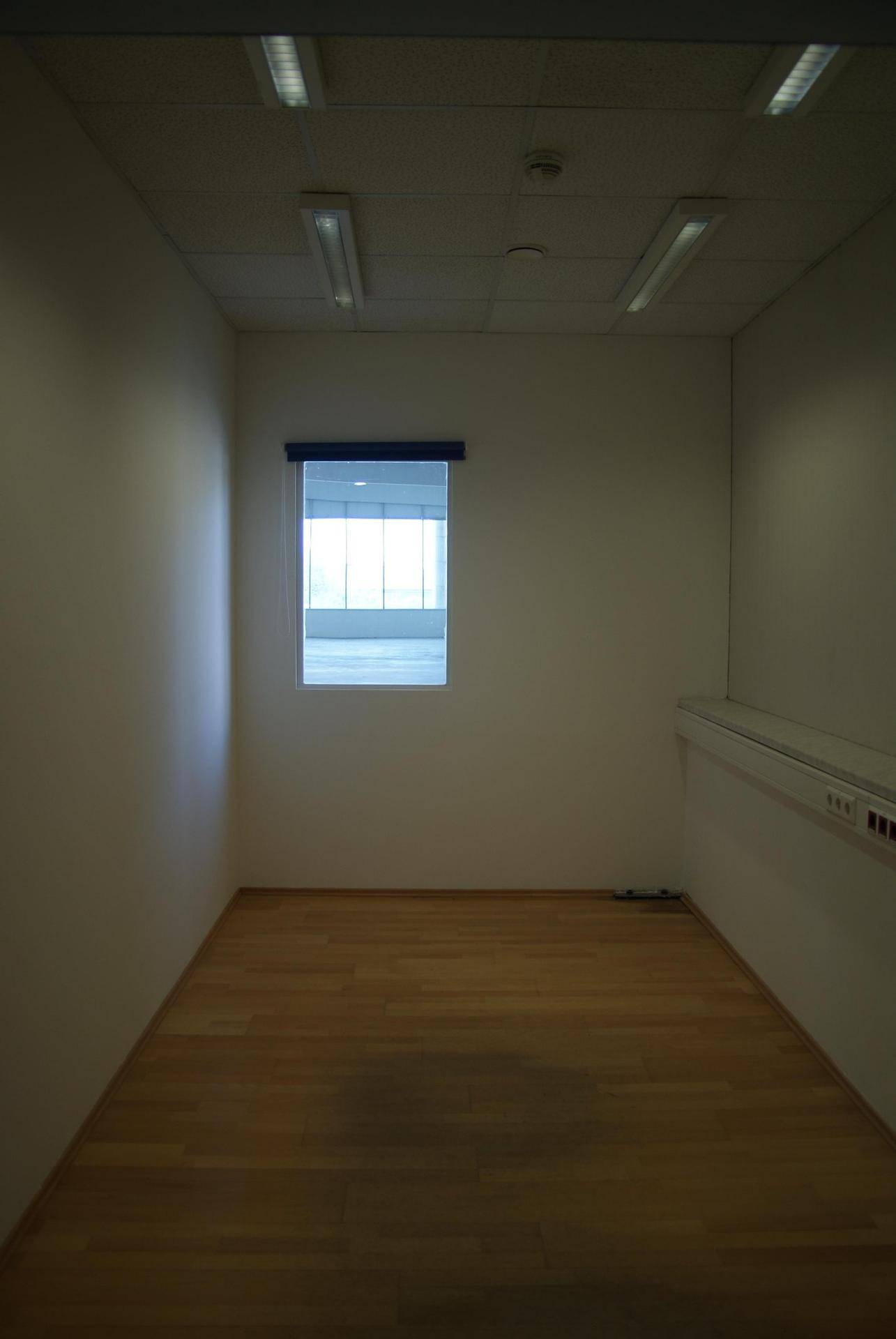 Kleiner, leerer Raum mit Holzfußboden und einem Fenster, das Tageslicht hereinlässt, ideal als Büro.