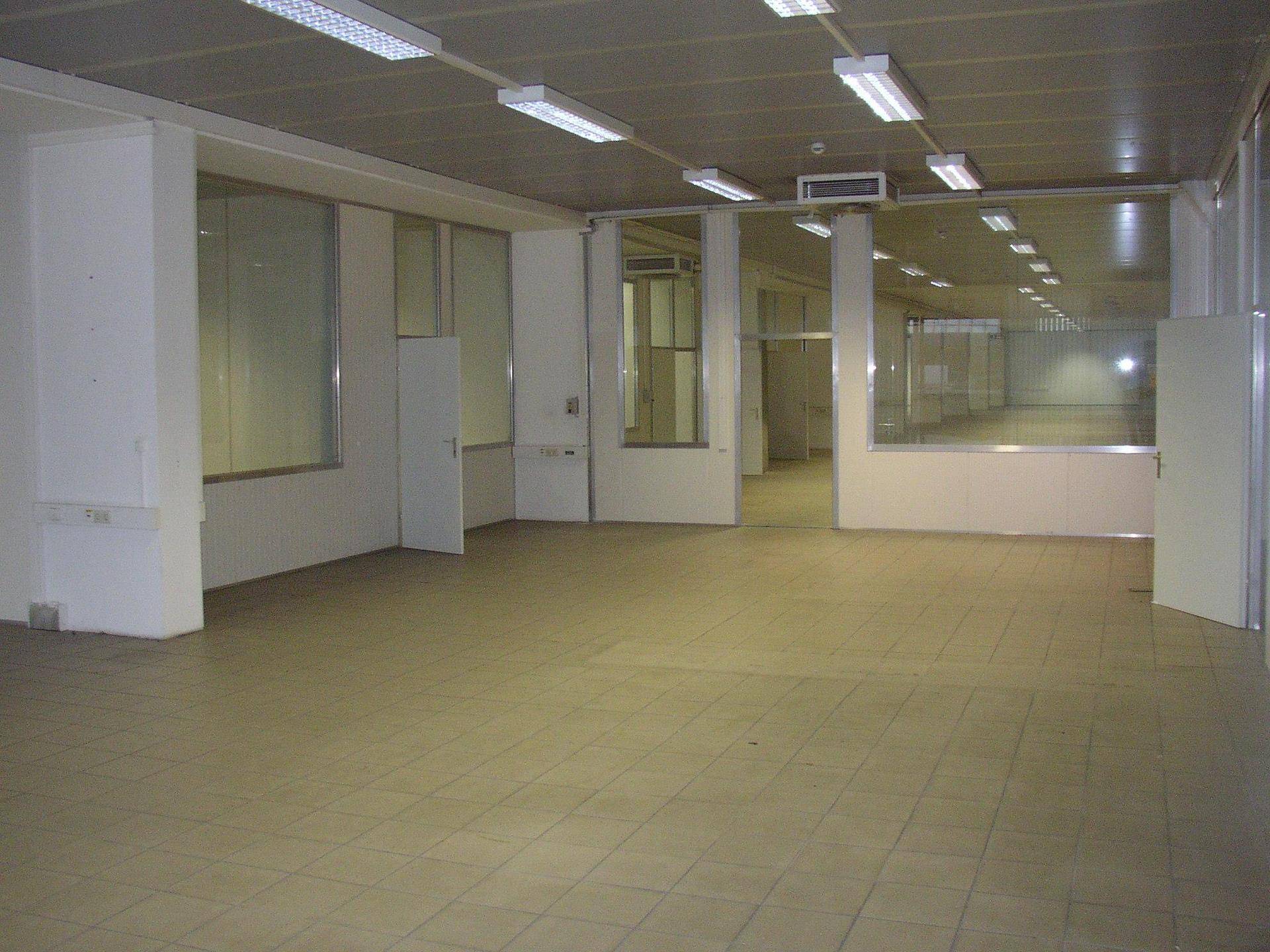 Geräumiger, leerer Gewerberaum mit Fliesenboden und abgehängter Decke, bereit zur Nutzung.