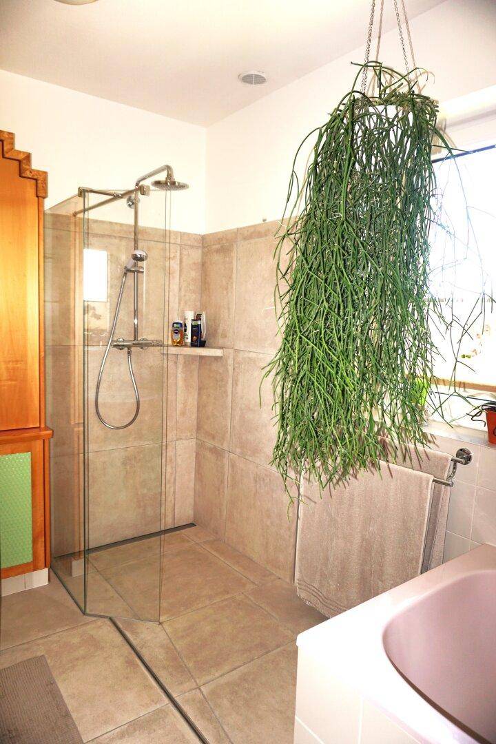 Modernes Badezimmer mit begehbarer Dusche, Badewanne und viel Tageslicht.