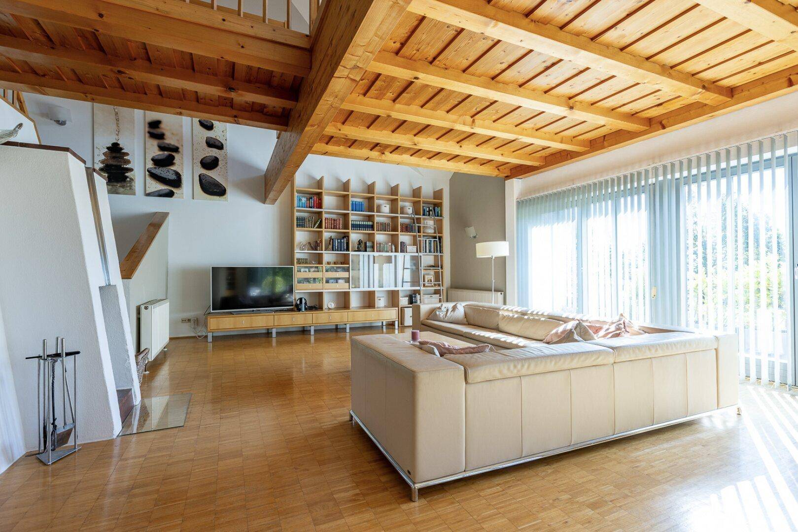 Großzügiges Wohnzimmer mit Holzbalkendecke, Parkettboden und Kamin.
