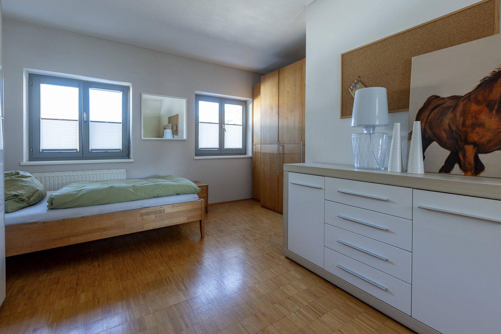 Gemütliches Schlafzimmer mit Holzbett, Parkettboden und Einbauschränken.