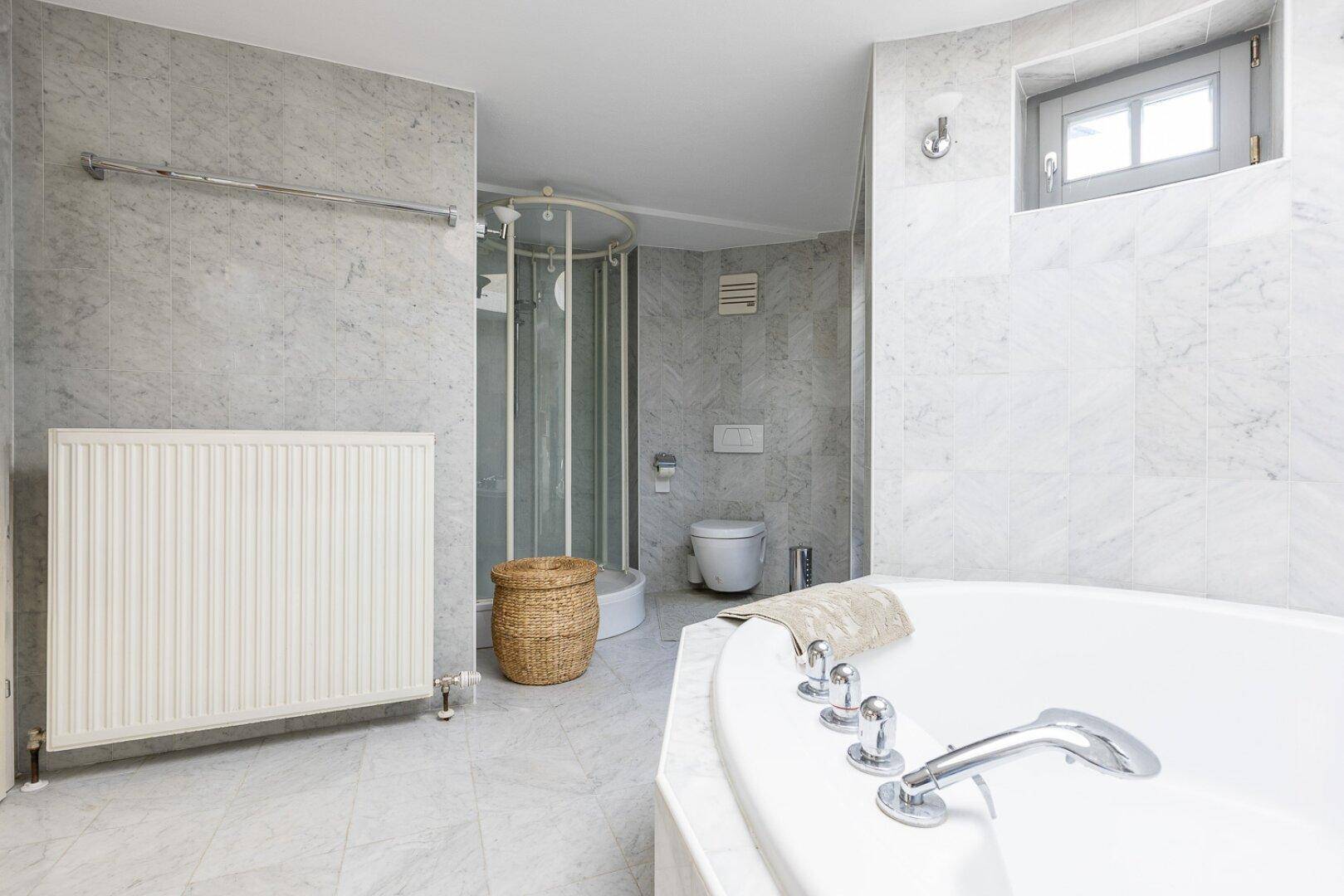 Geräumiges Badezimmer mit Eckbadewanne, Duschkabine und Marmorfliesen.