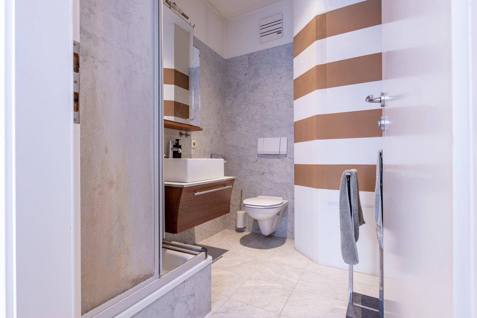Modernes Badezimmer mit Dusche, Hänge-WC und stilvollen Wandfliesen.