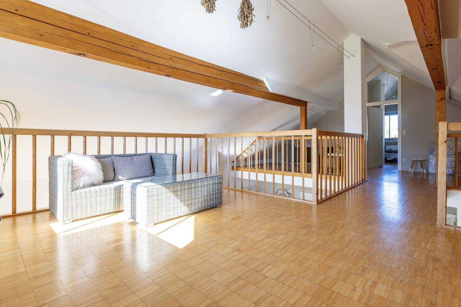 Offener Galeriebereich im Dachgeschoss mit Holzbalken und viel natürlichem Licht.