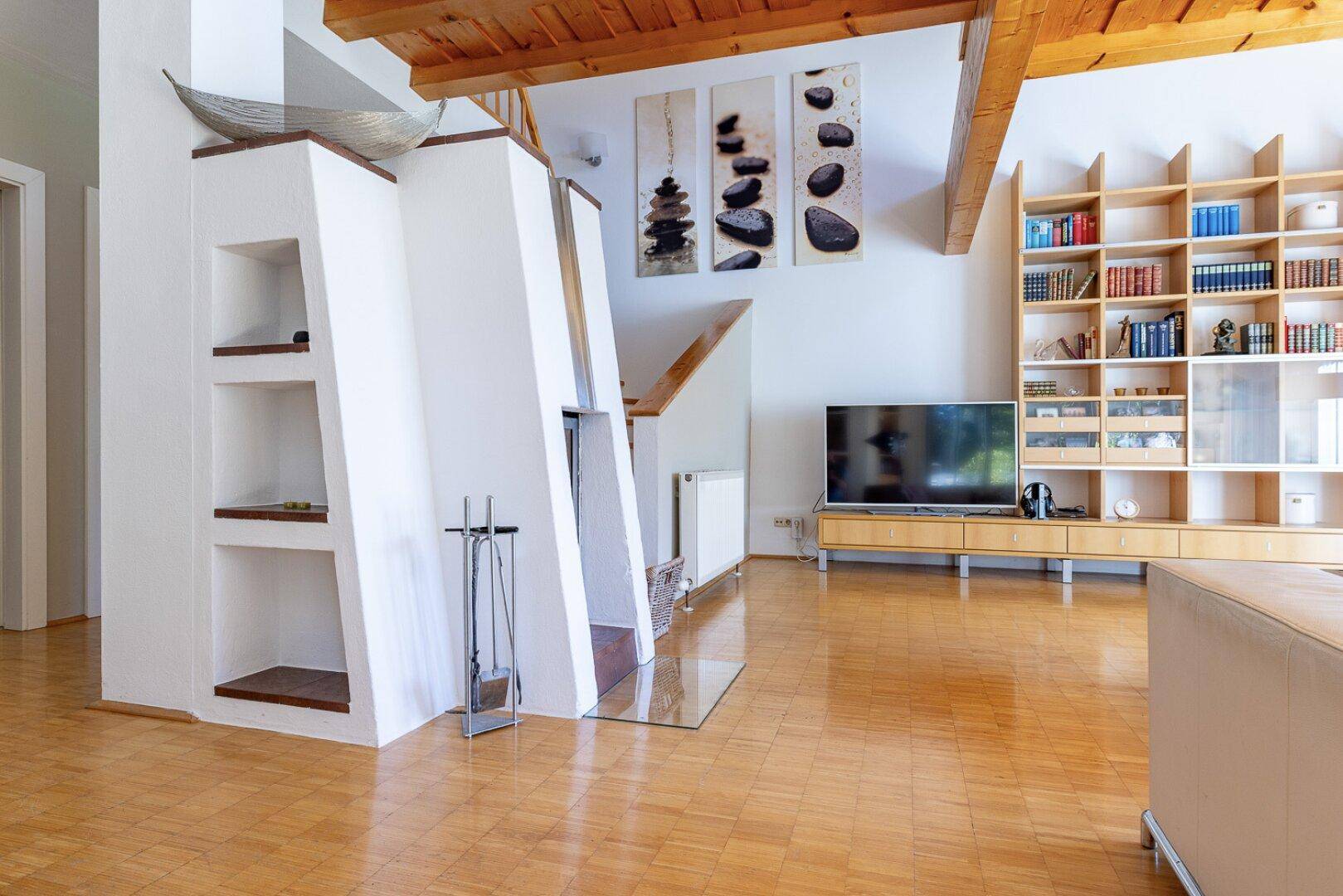 Geräumiges Wohnzimmer mit modernem Kamin, Holzboden und integriertem Bücherregal.