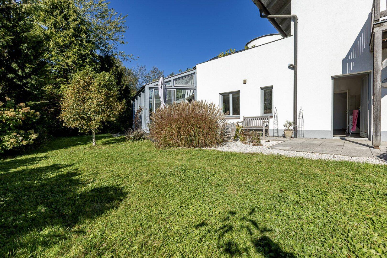 Gepflegter Gartenbereich neben dem Haus mit Rasenfläche und kleiner Terrasse.