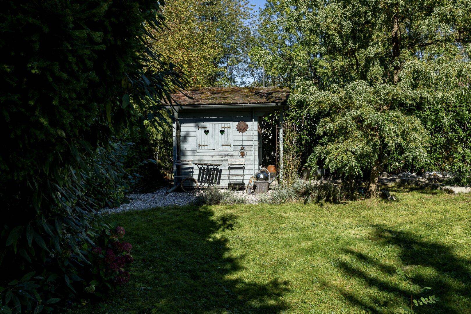 Idyllischer Garten mit einem kleinen Gartenhaus und einer gemütlichen Sitzecke im Grünen.