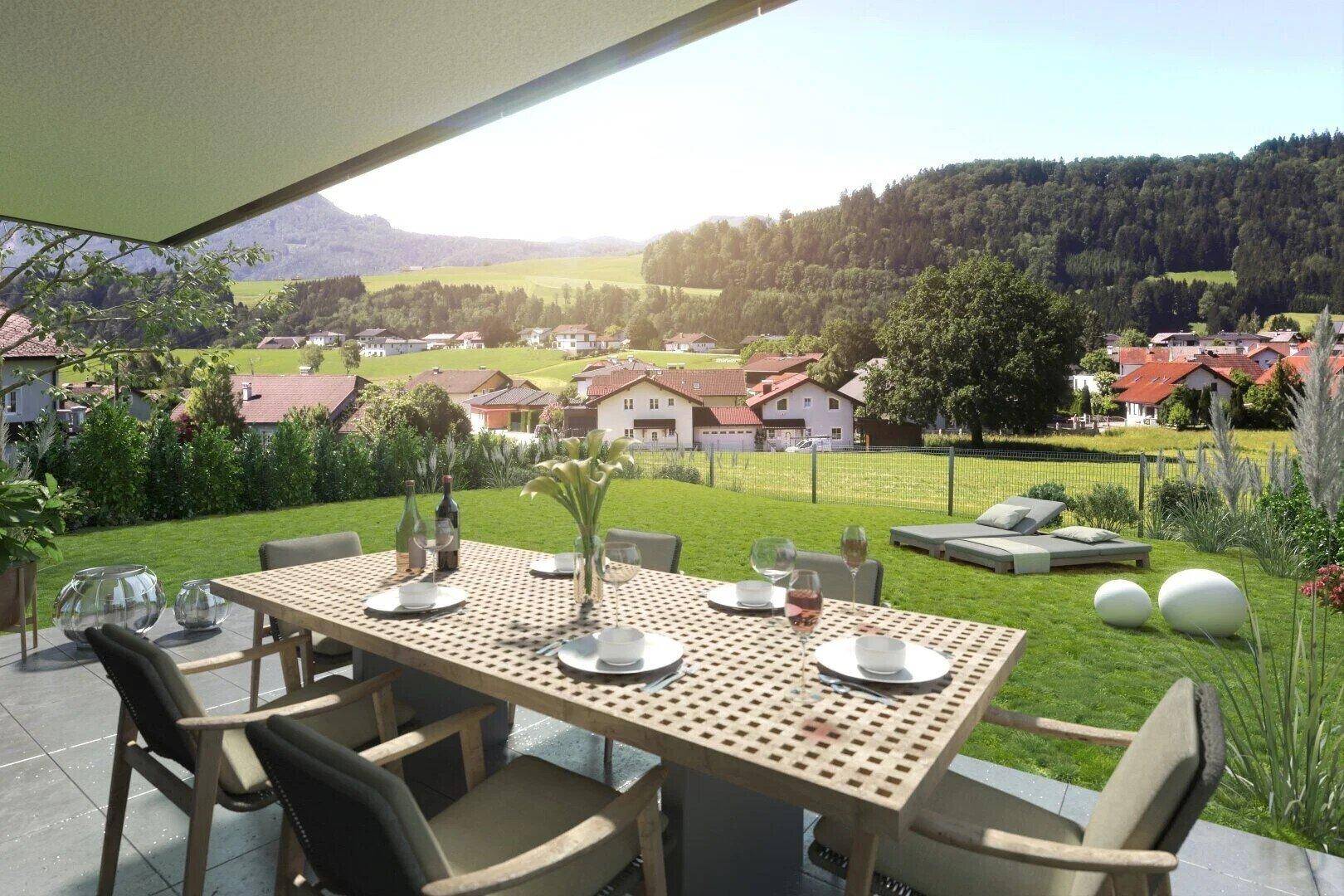 Sonnige Terrasse mit Esstisch und Gartenmöbeln, bietet einen weiten Blick auf die umliegende Landschaft und Berge.