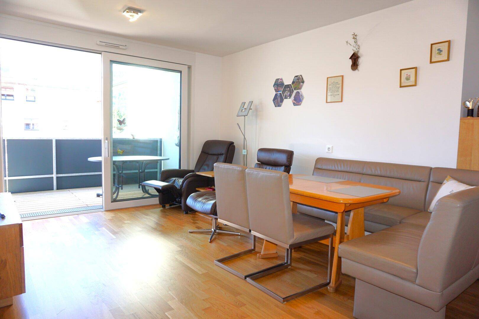 Heller Wohn- und Essbereich mit Holzboden und direktem Zugang zu einem Balkon.